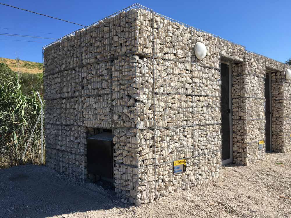 Parement de façade en gabions pour un poste de livraison sur le parc photovoltaïque de Lauzières dans le Gard